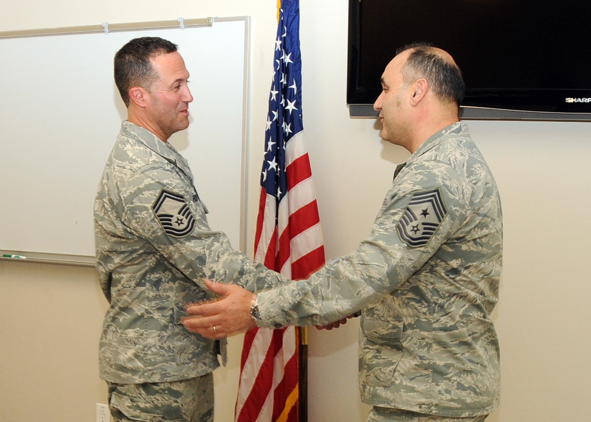 Command Chief Master Sergeant Jose Baltazar, Command Chief, 143d Airlift Wing, Rhode Island Air National Guard, presents Senior Master Sergeant Brian Robitaille, Fuels Management Flight Chief, 143d AW, with a challenge coin for his role in preparing for, executing and instructing at the inaugural Leadership Development Course held at Quonset Air National Guard Base, North Kingstown, Rhode Island on January 21, 2015. National Guard Photo by Master Sergeant Janeen Miller (RELEASED)
