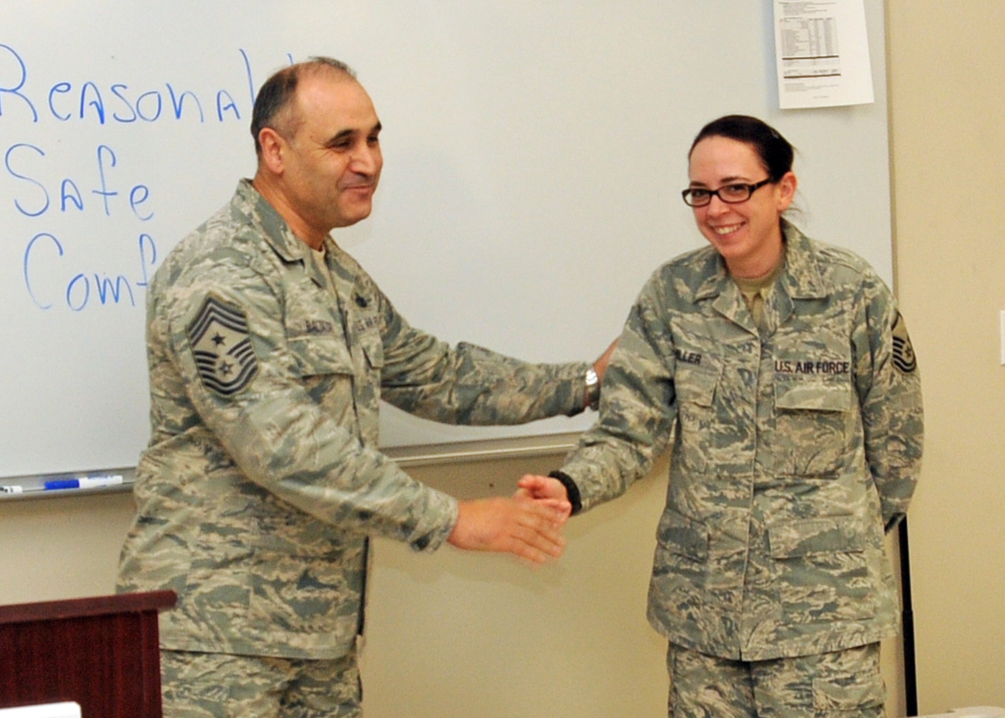 Command Chief Master Sergeant Jose Baltazar, Command Chief, 143d Airlift Wing, Rhode Island Air National Guard, presents Master Sergeant Janeen Miller, Public Affairs Manager, 143d AW, with a challenge coin for her role in preparing for, executing and instructing at the inaugural Leadership Development Course held at Quonset Air National Guard Base, North Kingstown, Rhode Island on January 21, 2015. National Guard Photo by Senior Master Sergeant Brian Robitaille