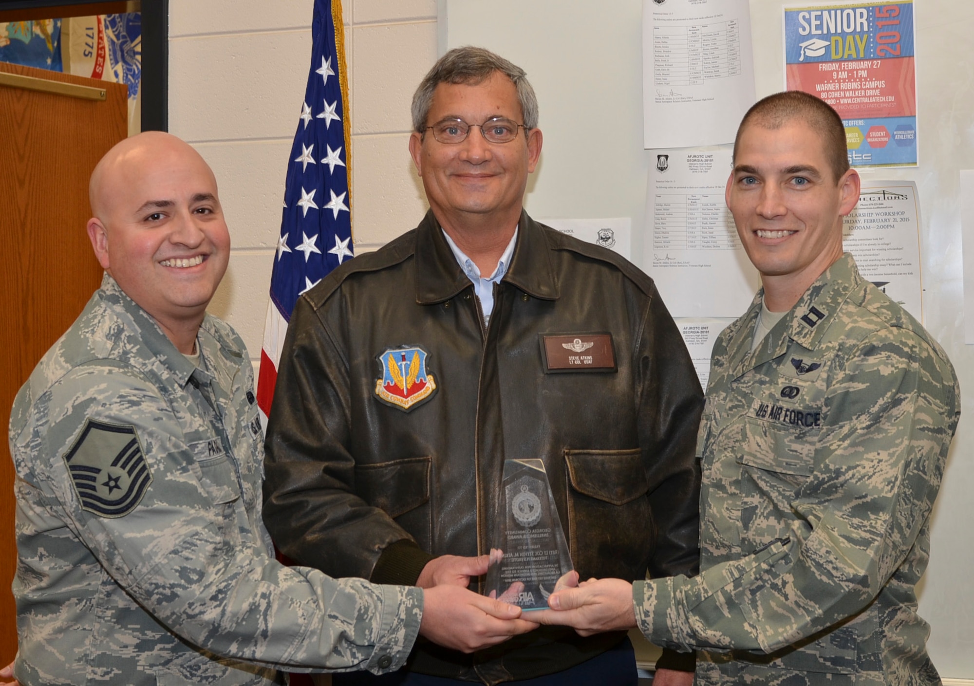 U.S. Air Force Capt. Daniel Spear, 116th Force Support  Squadron deputy commander, right, and Master Sgt. Jose Padilla, noncommissioned officer in charge of recruiting for the 116th Air Control Wing, Georgia Air National Guard, present U.S. Air Force retired, Lt. Col. Steve Atkins with a National Guard Bureau Community Influencer Award at Veteran’s High School, Kathleen, Ga., Feb. 12, 2015. Atkins, a senior aerospace science JROTC instructor, was honored in front of his class for his outstanding Air National Guard recruiting and retention support.  (U.S. Air National Guard photo by Tech. Sgt. Regina Young/Released)