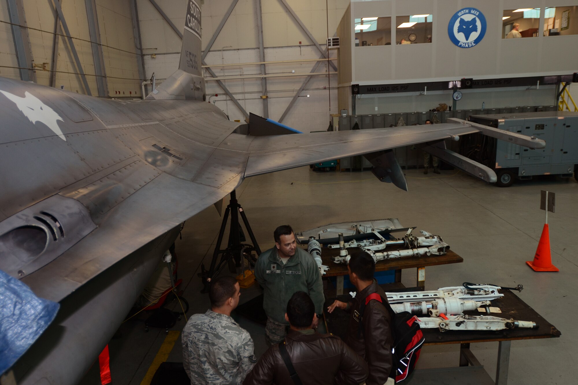 U.S. Air Force Maj. Brian Doyle, commander of the 169th Maintenance Operations Flight, discusses the intricacies of F-16 maintenance in the Phase Dock to Colombian Air Force maintenance officers Maj. Juan Gonzalez and Maj. Naily Ganem during a State Partnership Program (SPP) visit at McEntire Joint National Guard Base, S.C., Feb. 19, 2015. The Colombian Air Force sent a delegation of experts as a part of a three-day Key Leader Engagement and Subject Matter Expert exchange sharing information on flying and maintenance operations at McEntire JNGB and fostering relationships between the militaries. (U.S. Air National Guard photo by Senior Master Sgt. Edward Snyder/Released)