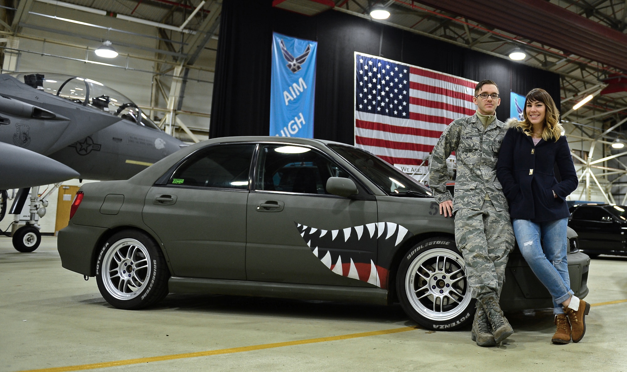 Senior Airman Mitchell Rose, 48th Logistics Readiness Squadron central storage technician, and his wife, Erin, pose with their 2002 Subaru WRX in Hangar 7 for a BBC Top Gear Magazine visit at Royal Air Force Lakenheath, England, Feb. 19, 2015. Rose painted his car as a tribute to the P-40 Warhawk fighter aircraft from World War II. Media visited the 48th Fighter Wing to put together a feature about Liberty Airmen and their cars. (U.S. Air Force photo by Airman 1st Class Erin R. Babis/Released)