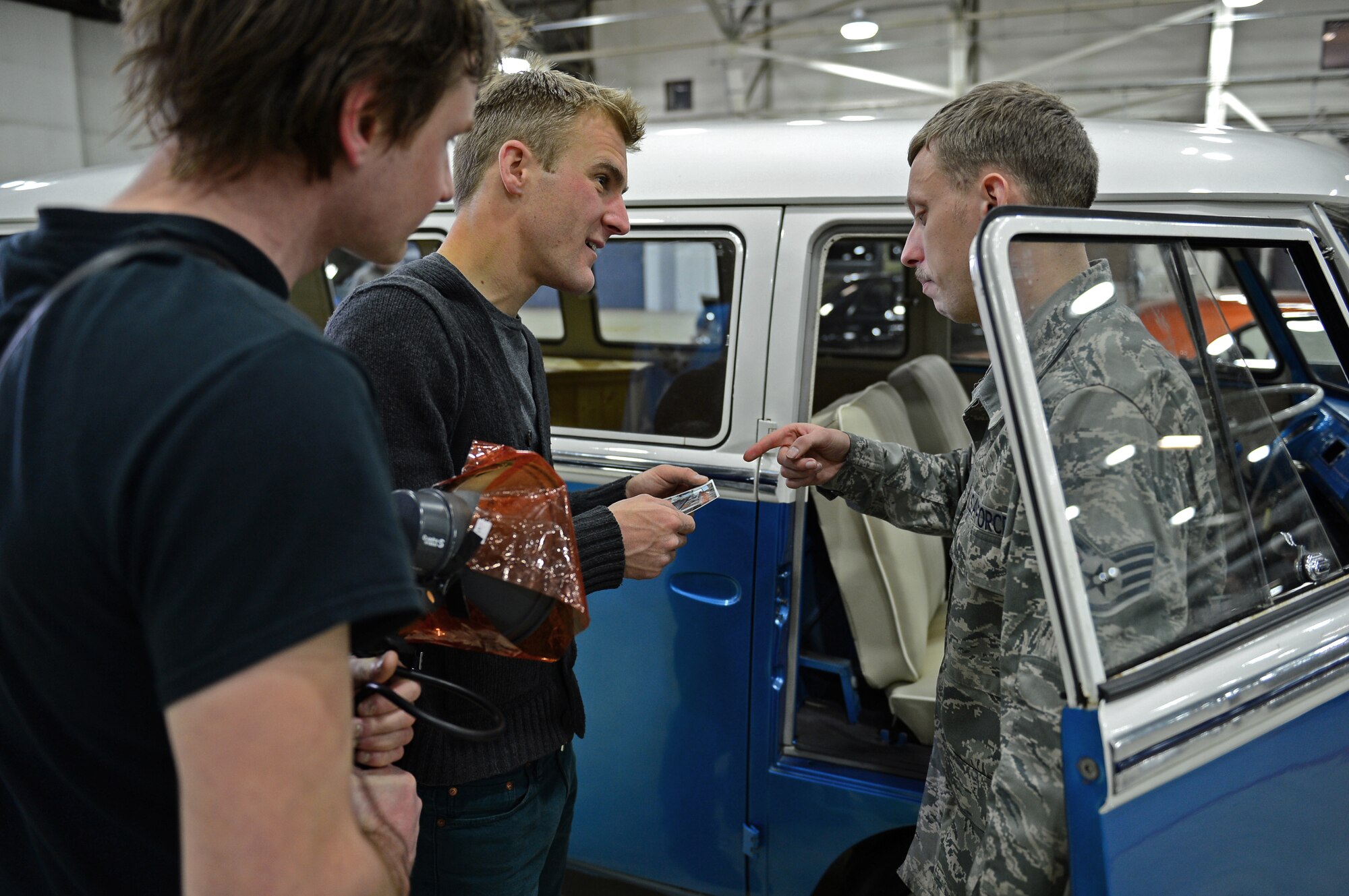 Staff Sgt. Andrew Dore, 48th Equipment Maintenance Squadron aerospace ground equipment craftsman, shows the before picture of his 1965 VW Bus to James Lipman, freelance photographer, and his assistant, Michael Jelinek, at Royal Air Force Lakenheath, England, Feb. 19, 2015. Media visited from BBC Top Gear Magazine to feature Liberty Airmen and their cars. Dore has been working on and repairing classic cars as a hobby for more than nine years. (U.S. Air Force photo by Airman 1st Class Erin R. Babis/Released)
