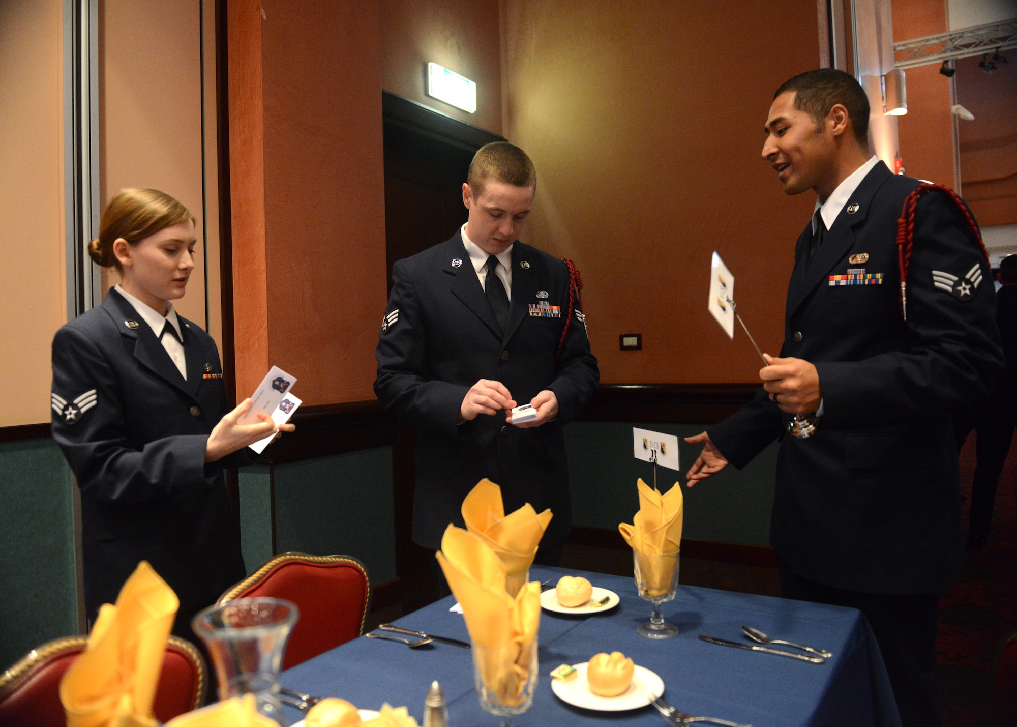 (From left) U.S. Air Force Senior Airmen Brooke and Adam Clark and Robert Sawyer, 31st Communications Squadron, set a table before an Airman Leadership School graduation, Feb. 12, 2015, at Aviano Air Base, Italy.  ALS, a five-week course, helps develop front-line supervisors through several blocks of instruction. (U.S. Air Force photo by Staff Sgt. Evelyn Chavez/Released) 