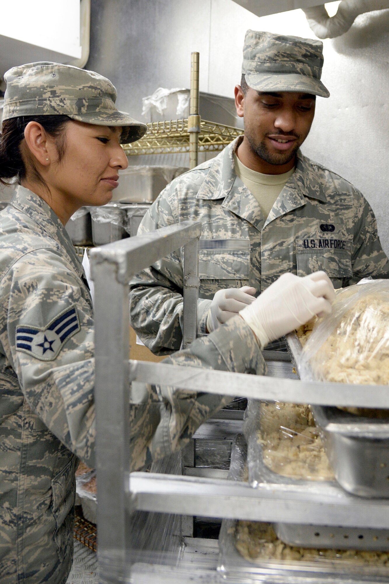Senior Airman Jovitamaria, left, and Senior Airman Sterling, Oasis quality assurance, inspect chopped chicken in the dining facility at an undisclosed location in Southwest Asia Feb. 17, 2015. The Airmen at the Oasis DFAC work around the clock to ensure that the Air Force’s greatest weapon system, the Airman, is fed. Jovitamaria is currently deployed from Beale Air Force Base, Calif., and is a native of San Diego, Calif. Sterling is currently deployed from Beale AFB, Calif., and is a native of Saint Louis, Mo. (U.S. Air Force photo illustration/Tech. Sgt. Marie Brown)