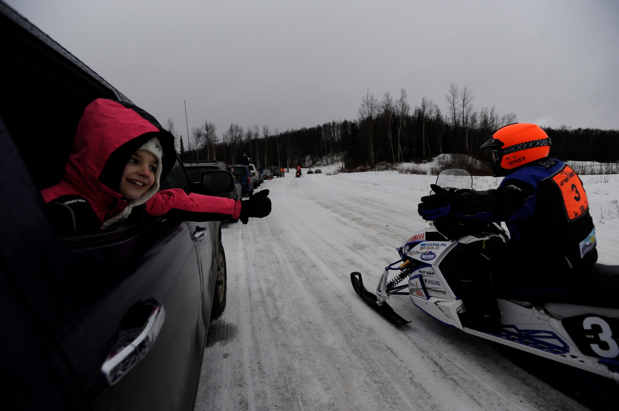 Payton Roach, 9, reaches out to touch an Iron Dog racer’s hand as they pass on Joint Base Elmendorf-Richardson, Alaska, Feb. 21. Payton is the daughter of Air Force Master Sgt. Charles Roach, 773d Logistics Readiness Squadron vehicle operations section chief. (U.S. Air Force photo/Tech. Sgt Robert Barnett)