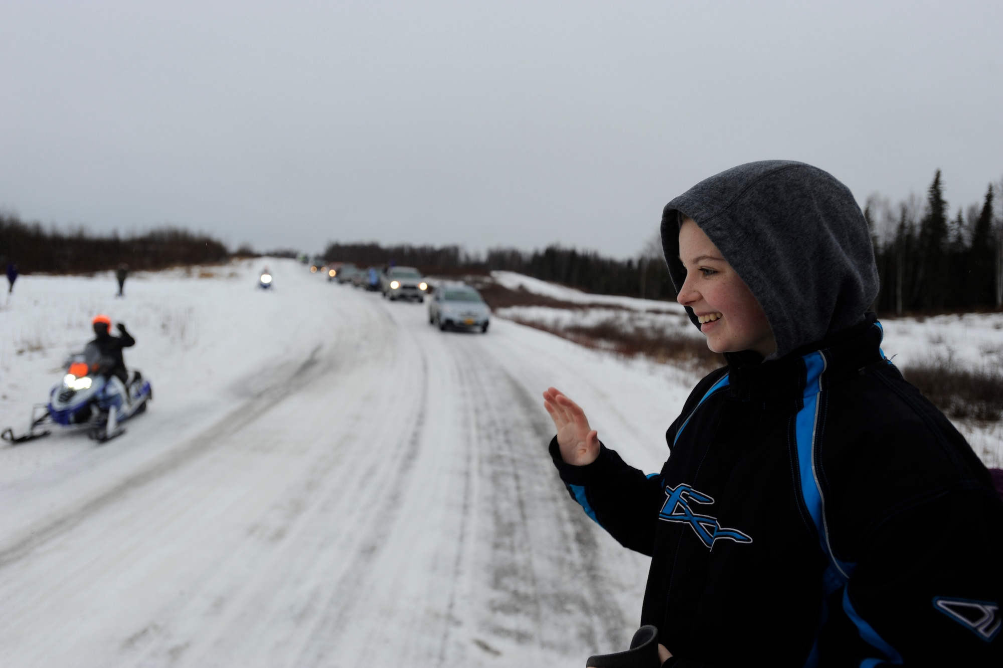 Morgan Roach, 15, waves as Iron Dog racers as they pass on Joint Base Elmendorf-Richardson, Alaska, Feb. 21. Morgan is the daughter of Air Force Master Sgt. Charles Roach, 773d Logistics Readiness Squadron vehicle operations section chief. “It was amazing,” she said. (U.S. Air Force photo/Tech. Sgt. Robert Barnett)