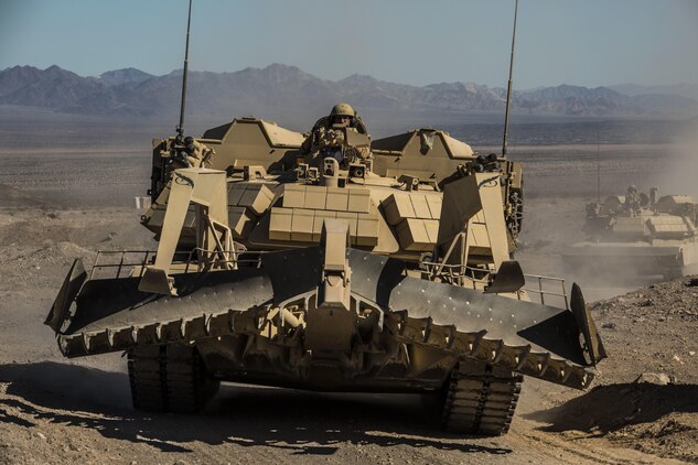 An assault breacher vehicle races towards the objective as artillery provides suppressing fire Feb. 9 at Marine Air Ground Combat Center Twentynine Palms, California, during the battalion assault course at Integrated Training Exercise 2-15. ABV’s are used to clear areas of mines and other ordinance for ground troops and vehicles to move through. During the BAC the ABV’s fire a mine-clearing line charge to simulate destroying enemy ordinance. The Marines operating the ABV are with 2nd Combat Engineer Battalion, 2nd Marine Division, II Marine Expeditionary Force. 