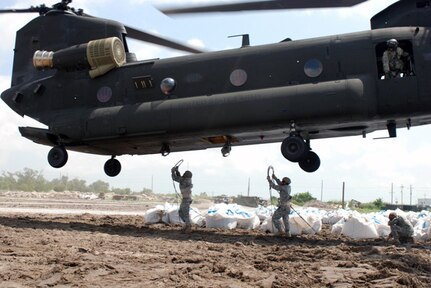 Louisiana National Guardsmen of the 205th Engineer Battalion hook sling cables, attached to sandbags to the bottom of a Florida National Guard CH-47 Chinook helicopter, in Buras, La., June 5, 2010.