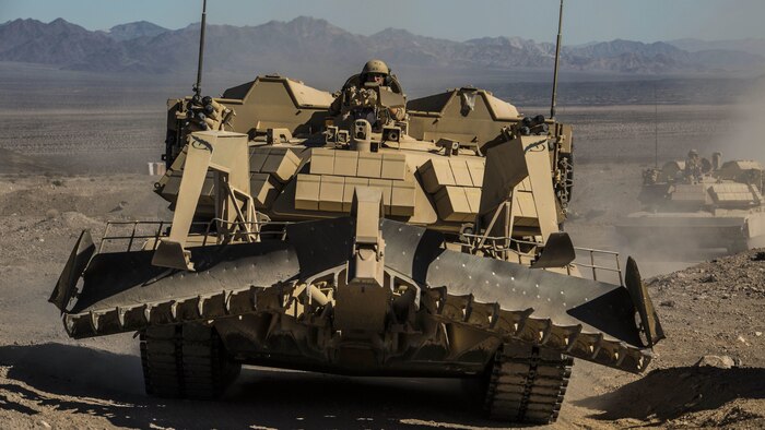 An assault breacher vehicle races towards the objective as artillery provides suppressing fire Feb. 9 at Marine Air Ground Combat Center Twentynine Palms, California, during the battalion assault course at Integrated Training Exercise 2-15. ABV’s are used to clear areas of mines and other ordinance for ground troops and vehicles to move through. During the BAC the ABV’s fire a mine-clearing line charge to simulate destroying enemy ordinance. The Marines operating the ABV are with 2nd Combat Engineer Battalion, 2nd Marine Division, II Marine Expeditionary Force. 