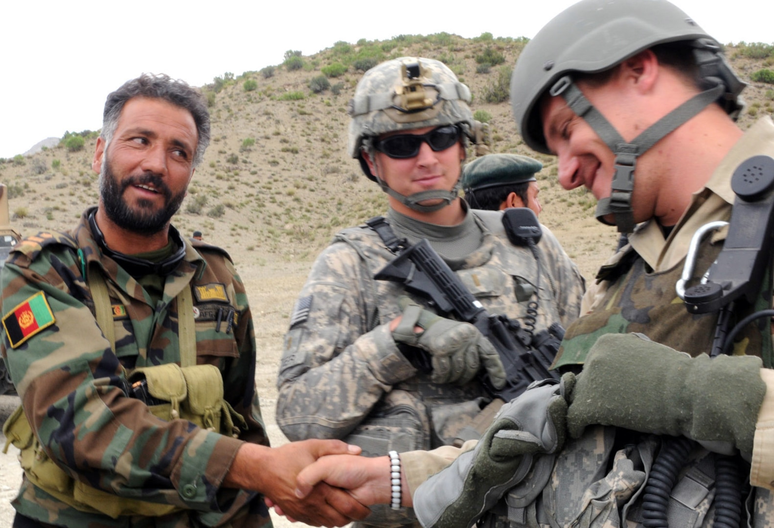 U.S. Army 2nd Lt. Dan Silver, platoon leader from Dover, N.H., of 4th Platoon, D Company, 3rd Battalion, 172nd Infantry Regiment smiles as his Macedonian counterpart Capt. Burche Turturov, the commander of the Macedonian Ranger Platoon from Skopje, Macedonia, shakes hands with an Afghan National Army soldier during a patrol, June 5. The Macedonians are embedded with the D Company Soldiers of the Vermont National Guard as part of their state Partnership for Peace Program. They are the first state partnership involved in the program to embed and run combat operations.