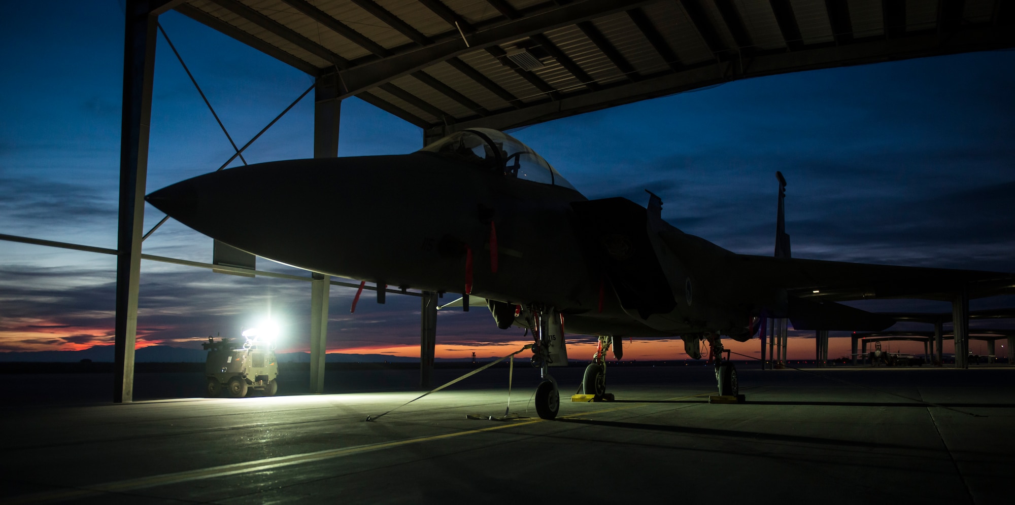 An F-15E Strike Eagle sits in the shadows at Mountain Home Air Force Base Idaho Feb. 19, 2015. The gloomy light supplied by old Light-All lamps were all maintainers and flightline workers had to work in. However, newly renovated lights illuminate the first four rows of aircraft shelters creating a well lit environment so Airmen can work safely and more efficiently. (U.S. Air Force photo by Airman Connor J. Marth/RELEASED)