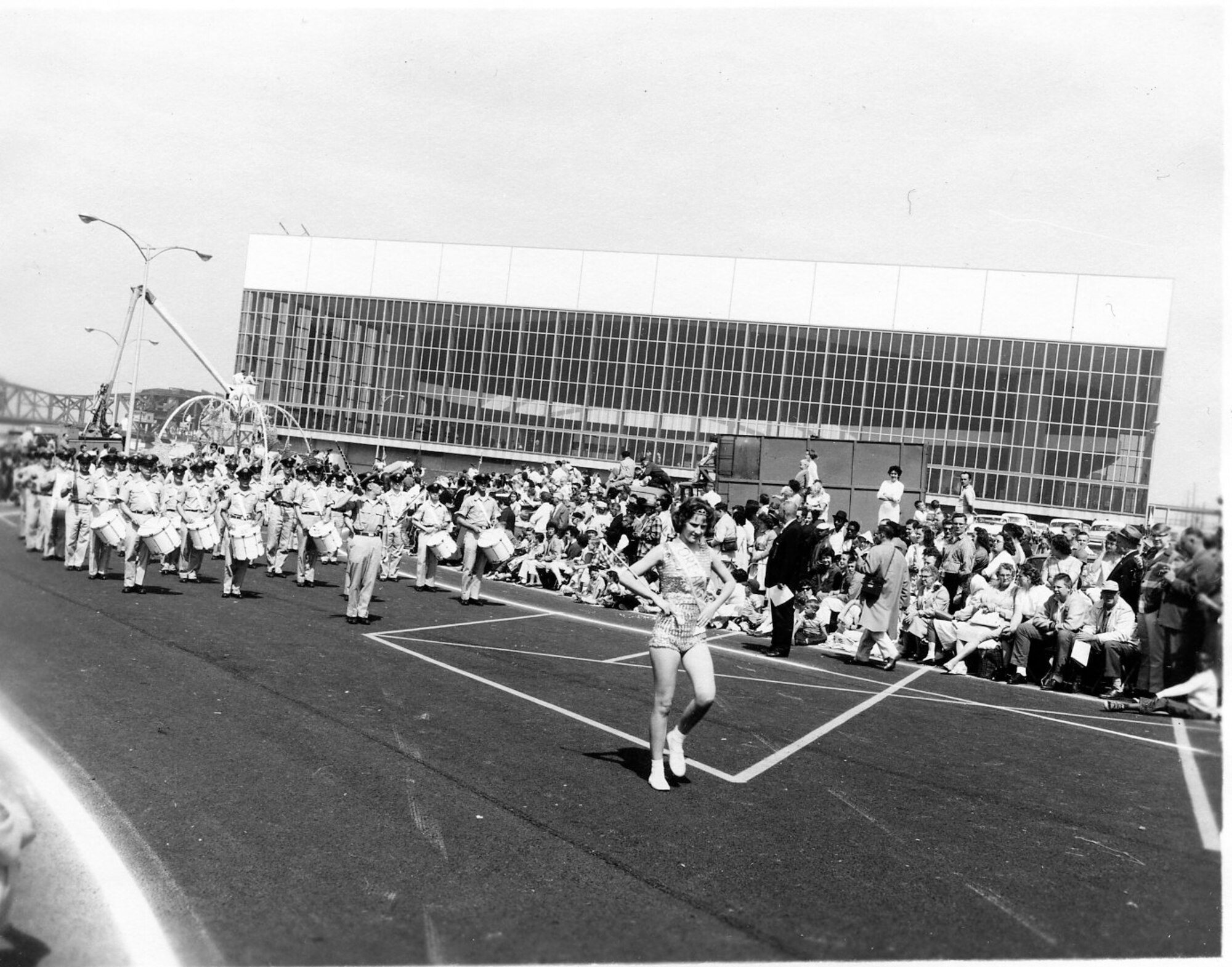 The OreANG Drum & Bugle Corps passes by the Veterans Memorial Coliseum during the Rose Festival’s Grand Floral Parade which took place June 10, 1961. Note the old Steel Bridge in the background at left.