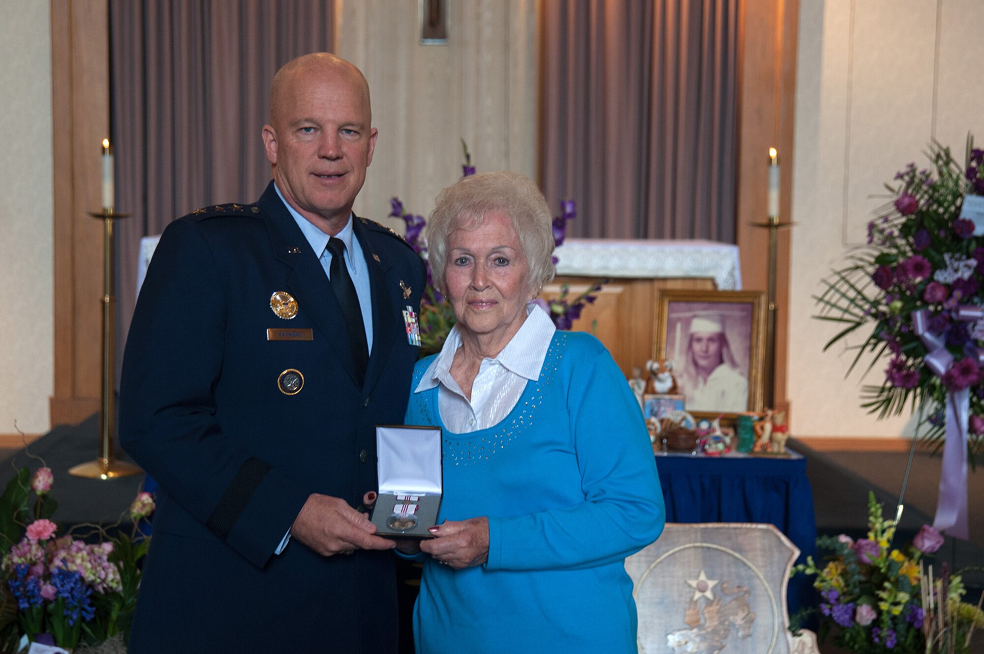 U.S. Air Force Lt. Gen. Jay Raymond, commander, 14th Air Force (Air Forces Strategic) and Joint Functional Component Command for Space, presents the Outstanding Civilian Career Service Award to Betty Flynn during a memorial service for her daughter, Tammy Martin, Feb. 19, 2015, at the base chapel.  The 14th Air Force Commander’s Secretary since 1998, “Ms. Tammy,” as she was known, was celebrating her 40th year as a civil servant at the time of her passing from a sudden illness, Feb. 12, 2015.  (U.S. Air Force photo by Michael Peterson/Released)