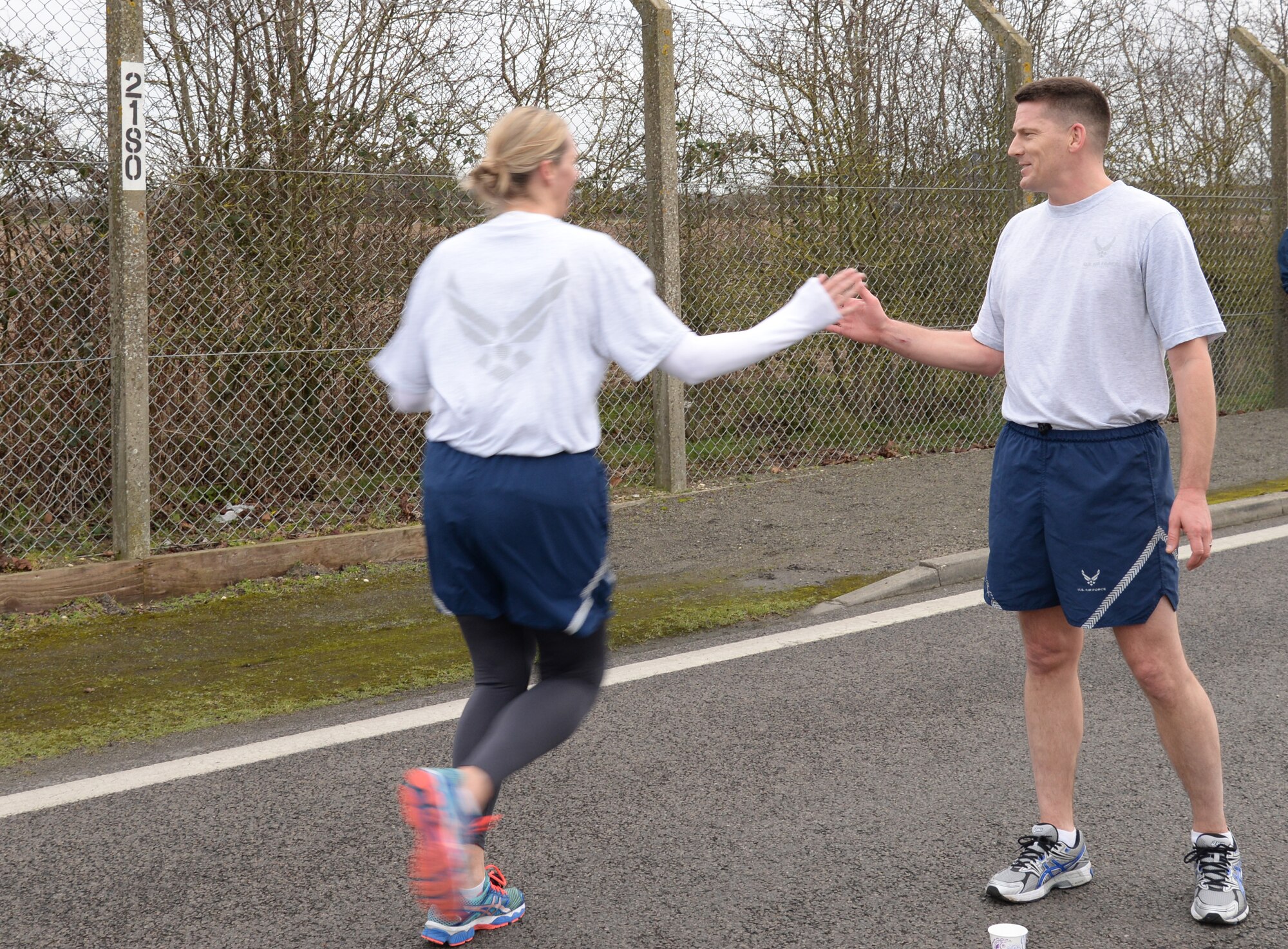 U.S. Air Force Chief Master Sgt. Tracy Jones, right, 100th Air Refueling Wing command chief, high-fives a Team Mildenhall member as they finish the monthly 5 km run Feb. 20, 2015, on RAF Mildenhall, England. Service members, civilians and their families participated in the 5 km run. (U.S. Air Force photo by Airman 1st Class Jonathan Light/Released) 