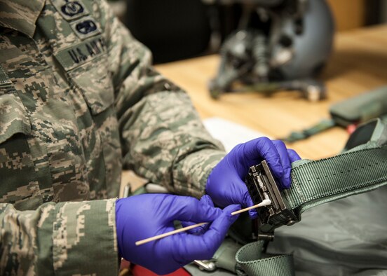 Staff Sgt. Karol Carmona, of the 96th Operations Support Squadron, applies lubricant with a cotton swab to the ejection seat release fittings on a flight torso harness at the Aircrew Flight Equipment facility on Eglin Air Force Base, Fla., Feb. 9. AFE technicians perform pre and post flight inspections of the torso harnesses.  In addition, the torso harnesses receive additional inspections and lubrication every 180 days.  The torso harness is the connection point between the aircrew member and their parachute.  (U.S. Air Force photo/Ilka Cole)  
