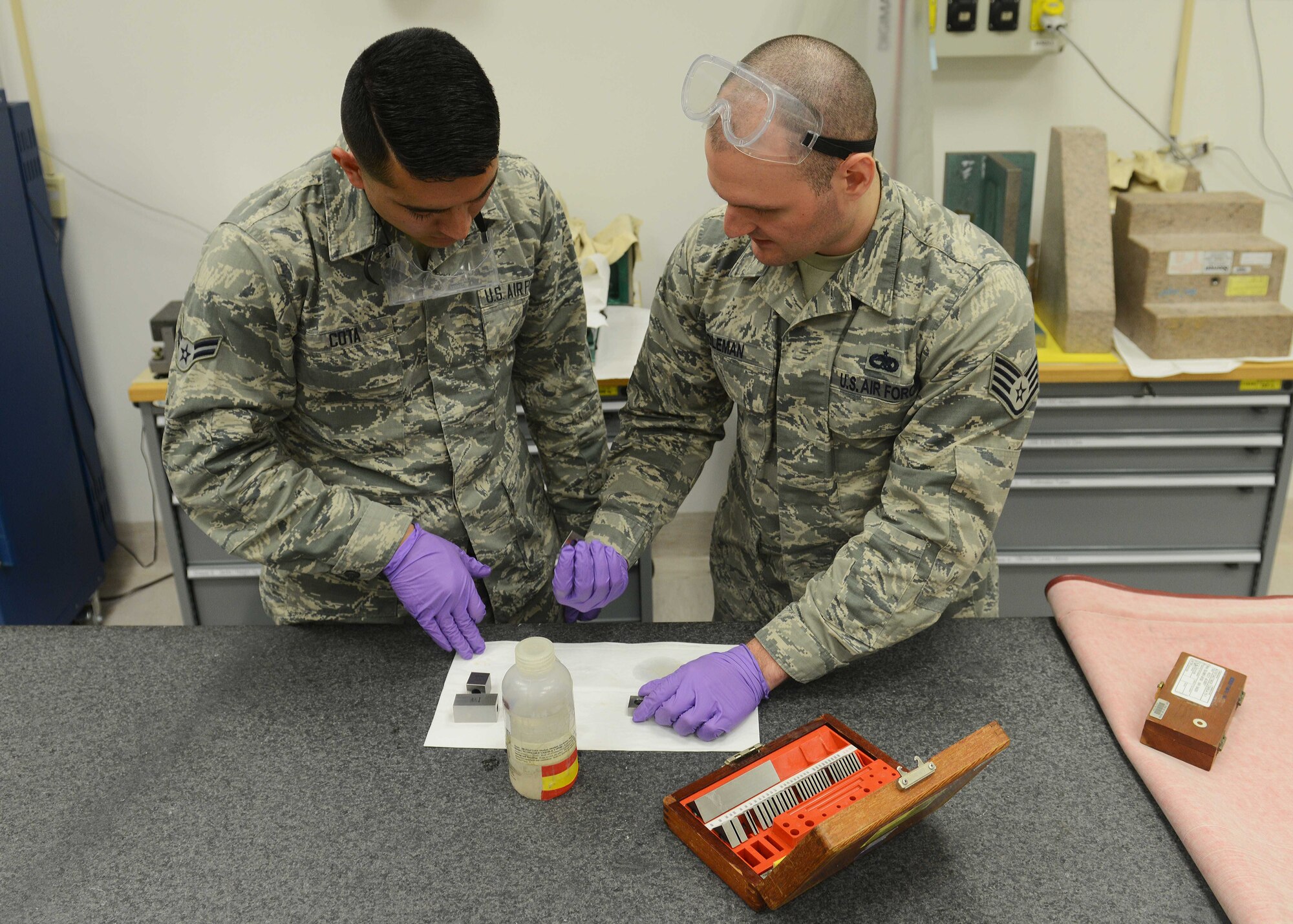 (From left) U.S. Air Force Airman 1st Class Juanluis Cota, 31st Maintenance Squadron crew chief, watches as Staff Sgt. Brian Coleman, 31 MXS precision measurement equipment laboratory craftsman, demonstrates how to calibrate a micrometer, Feb. 17, 2015, at Aviano Air Base, Italy. Cota participated in the Airmen Mentoring Airmen program which allows Airmen to explore what each shop within the squadron entails and how they directly impact the mission. (U.S. Air Force photo by Airman 1st Class Deana Heitzman/Released)