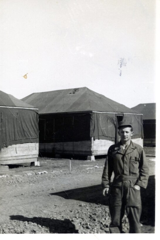 1952 photo of Amn Horace K. Pope of 118th ACW standing in front of the temporary quarters at Nouasseur AB, NorthAfrica.  The 118th built "Dallas Huts" to replace this temporary "Tent City."   (Photo by NCANG Heritage Program)