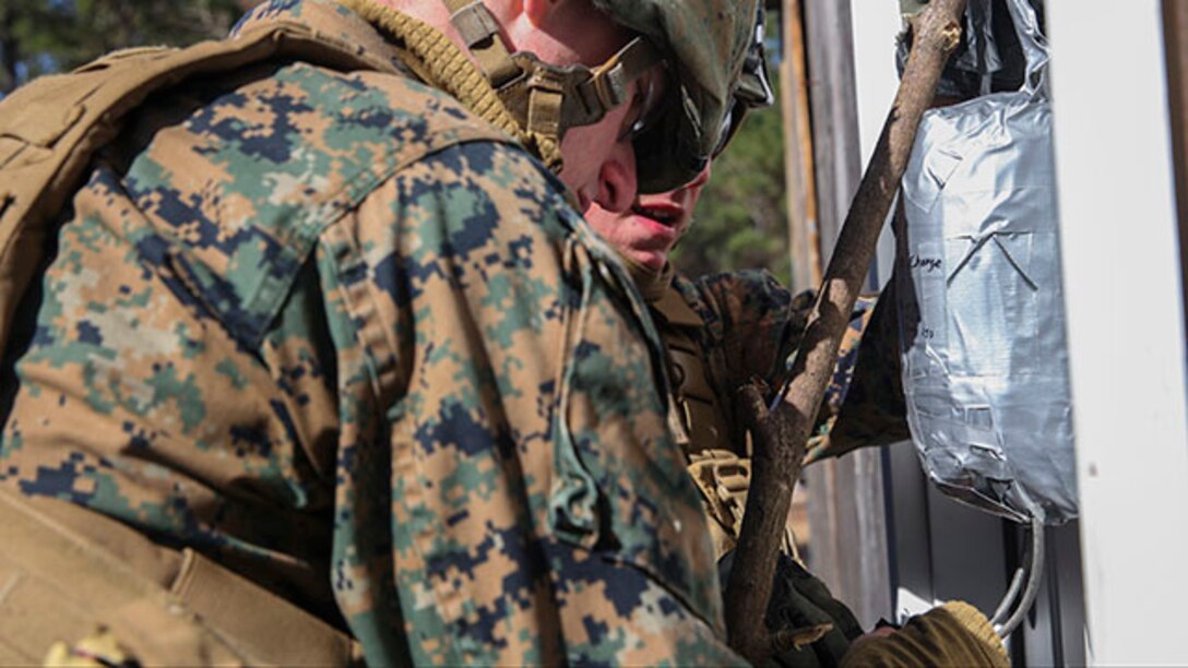 Two Marines with 2nd Combat Engineer Battalion set up an explosive charge that will blast open the locked door during their urban breaching training exercise on Engineer Training Area-1 aboard Marine Corps Base Camp Lejeune, N.C., Feb. 19, 2015. During the training, the unit learned how to open any type of door, gate or roof using a variety of tools, from explosives to shotguns and sledge hammers. They learned to do whatever was necessary to allow the infantry squad they were supporting to enter the building.