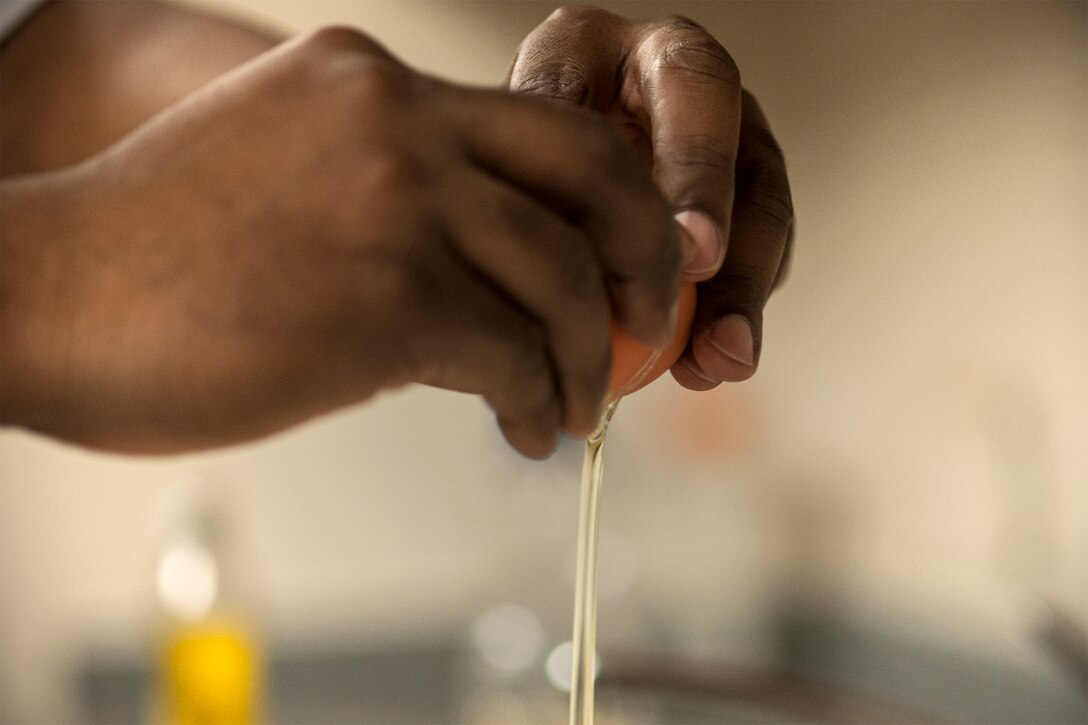 Staff Sgt. Lawyer Evans, 8th Logistics Readiness Squadron supply technician assistant NCO in charge, also known as “Cake Boss,” cracks open an egg as he bakes a cake Feb. 17, 2015, at Kunsan Air Base, Republic of Korea. Evans cooks more than a dozen cakes every month for individuals, organizations and events, including promotion celebrations, squadron barbecues and birthdays. (U.S. Air Force photo by Senior Airman Katrina Heikkinen/Released)