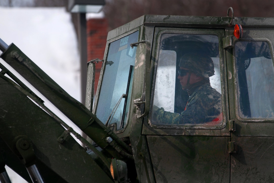 Army National Guard Spc. Jonathan Melanson dumps snow from his front end loader into a military dump truck during snow removal operations in Weymouth, Mass., Feb. 21, 2015. Melanson is a concrete and asphalt equipment operator assigned to the Massachusetts National Guard's 189th Engineer Company, 181st Engineer Battalion.
