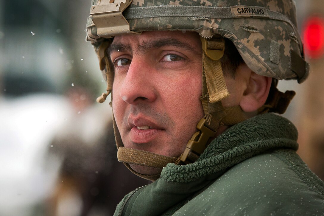 Army National Guard Spc. Gary Carvalho monitors traffic during snow removal operations at the Brigham Circle Massachusetts Bay Transportation Authority train stop in Boston, Feb. 17, 2015. Carvalho is assigned to the Massachusetts National Guard's 181st Engineer Company.