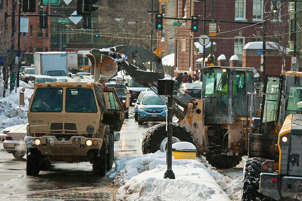 Soldiers operate dump trucks as they remove snow at the Brigham Circle