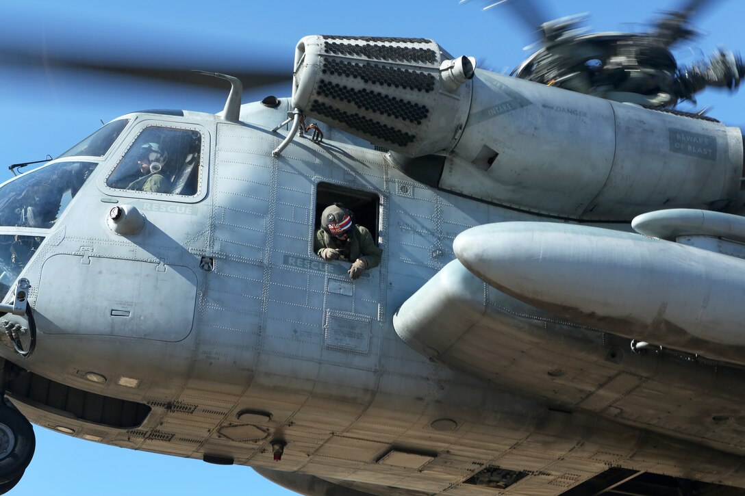 A Marine checks for clearance out the window of a Sikorsky CH-53 Super Stallion helicopter preparing for landing in support of a helicopter support team mission on Camp Lejeune, N.C., Feb. 18, 2015.