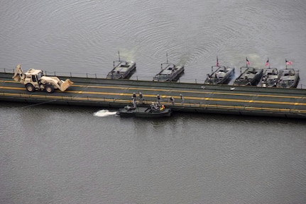 Soldiers of the North Dakota Army National Guard’s 957th Engineer Company (Multi-Role Bridge Company) work on securing the Improved Ribbon Bridge (IRB) emplaced on the Missouri River south of Bismarck, N.D., June 10-11, 2010. MKII Bridge Erection Boats (BEB) are depicted on both sides of the bridge as a backhoe is crossing the bridge. The 957th participated in an evaluation of the new “Thrust and Shore Guy” anchorage system with Product Manager Bridging, Tank-Automotive and Armaments Command (TACOM), TACOM Research, Development and Engineer Center (TARDEC), Maneuver Support Center of Excellence, and the National Guard Bureau.