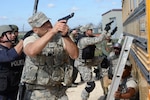 Staff Sgt. Paul Olmos III, 802nd Security Forces Squadron military working dog handler, leads members from the 902nd and 802nd SFS with members of local police departments during a bus assault and hostage rescue exercise Feb. 19, 2015 at Joint Base San Antonio-Randolph Camp Talon. The local agencies involved in the exercise were from the cities of Live, Oak Universal City and Converse and the Judson Independent School District Police Departments. Security Forces and local police departments trained together to prepare for emergencies that require both military and civilian response efforts. (U.S. Air Force photo by Airman 1st Class Stormy Archer/Released)