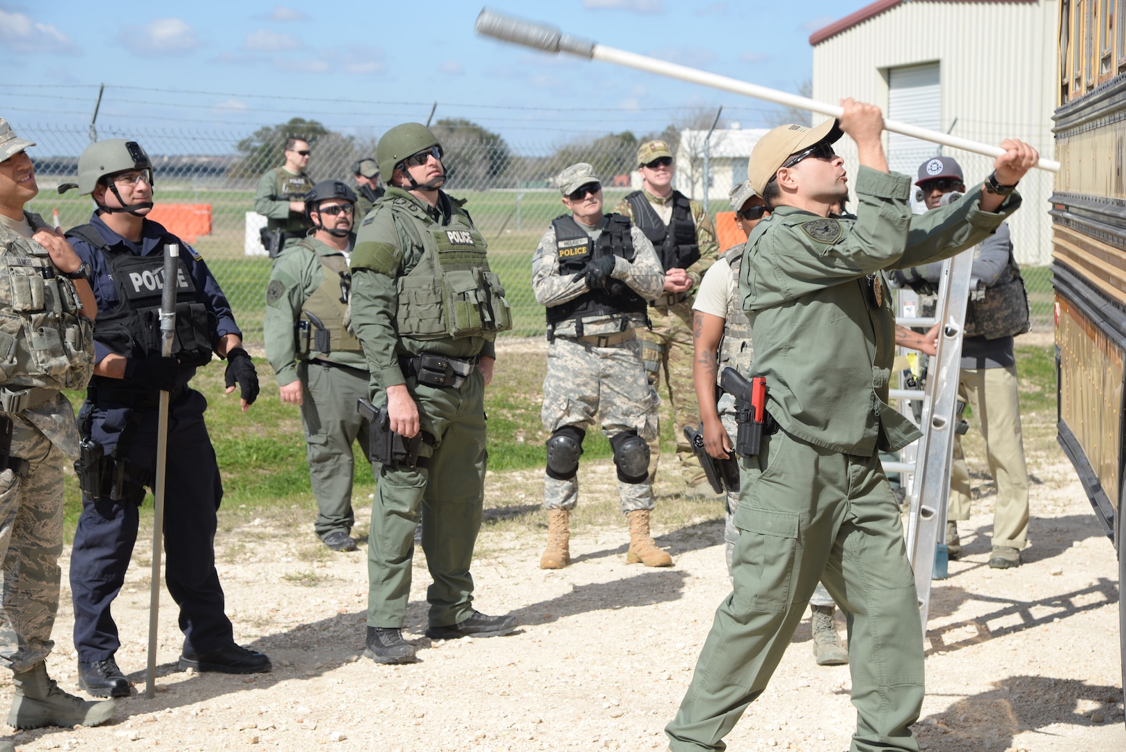 Tech. Sgt. Ruben Morales, 902nd Security Forces Squadron patrolman, demonstrates how to break a bus window during a bus assault and hostage rescue exercise Feb. 19, 2015, at Joint Base San Antonio-Randolph Camp Talon. The local agencies involved in the exercise were from the cities of Live, Oak Universal City and Converse and the Judson Independent School District Police Departments. Security Forces and local police departments trained together to prepare for emergencies that require both military and civilian response efforts. (U.S. Air Force photo by Airman 1st Class Stormy Archer/Released)
