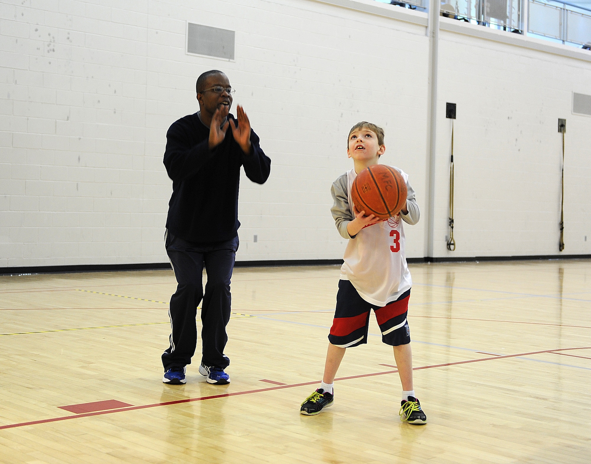 MINOT AIR FORCE BASE, N.D. -- Master Sgt. Marlin Stevenson, 5th Operations Support Squadron, first sergeant, helps a young boy during the Special Olympics basketball tournament at the McAdoo Fitness Center on Minot Air Force Base, N.D., Feb. 21, 2015. The Special Olympics athletes competed in various challenges to include shooting and dribbling. (U.S. Air Force photo/Senior Airman Kristoffer Kaubisch) 