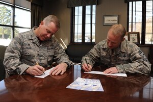 U.S. Air Force Col. John J. Allen, 633rd Air Base Wing commander, and Chief Master Sgt. Mark Hurst, 633rd ABW command chief, sign donation slips for the Air Force Assistance Fund at Langley Air Force Base, Va., Feb. 20, 2015. The AFAF is an annual campaign which aims to raise money to benefit four charitable organizations that support Air Force families in need. The charities supported by AFAF included the Air Force Villages program, which offers affordable retirement community for widowed spouses of retired Air Force officers; the Air Force Aid Society, which provides emergency assistance, educational aid and community programs; the Gen. and Mrs. Curtis E. LeMay Foundation, which aides both officers and enlisted widows and widowers with financial grants; and the Air Force Enlisted Village, which provides a secure place for financially-challenged surviving spouses of retired Air Force personnel, enlisted and officers. (U.S. Air Force photo by Staff Sgt. Stephanie R. Plichta/Released)