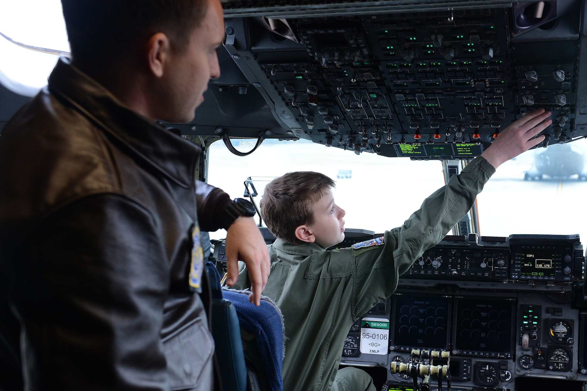 Carver Faull (right) explores the  buttons in the cockpit of a C-17 Globemaster III with 1st Lt. Brit Reuscher, 4th Airlift Squadron C-17 pilot, at Joint base Lewis-McChord, Wash. Feb. 20, 2015. Carver spent the day with members of McChord Field as part of the Pilot for a Day Program. (U.S. Air Force photo/Staff Sgt. Tim Chacon)