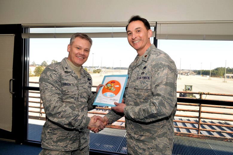 Maj. Joseph Whittington, 3rd Aerial Port Squadron commander, presents a lithograph of the squadron’s patch to Brig. Gen. Tim Gibson, U.S. Air Force Expeditionary Center vice commander, during Gibson’s visit to the 43rd Airlift Group, Pope Army Airfield, N.C. Feb. 19-20. (U.S. Air Force photo/Marvin Krause)