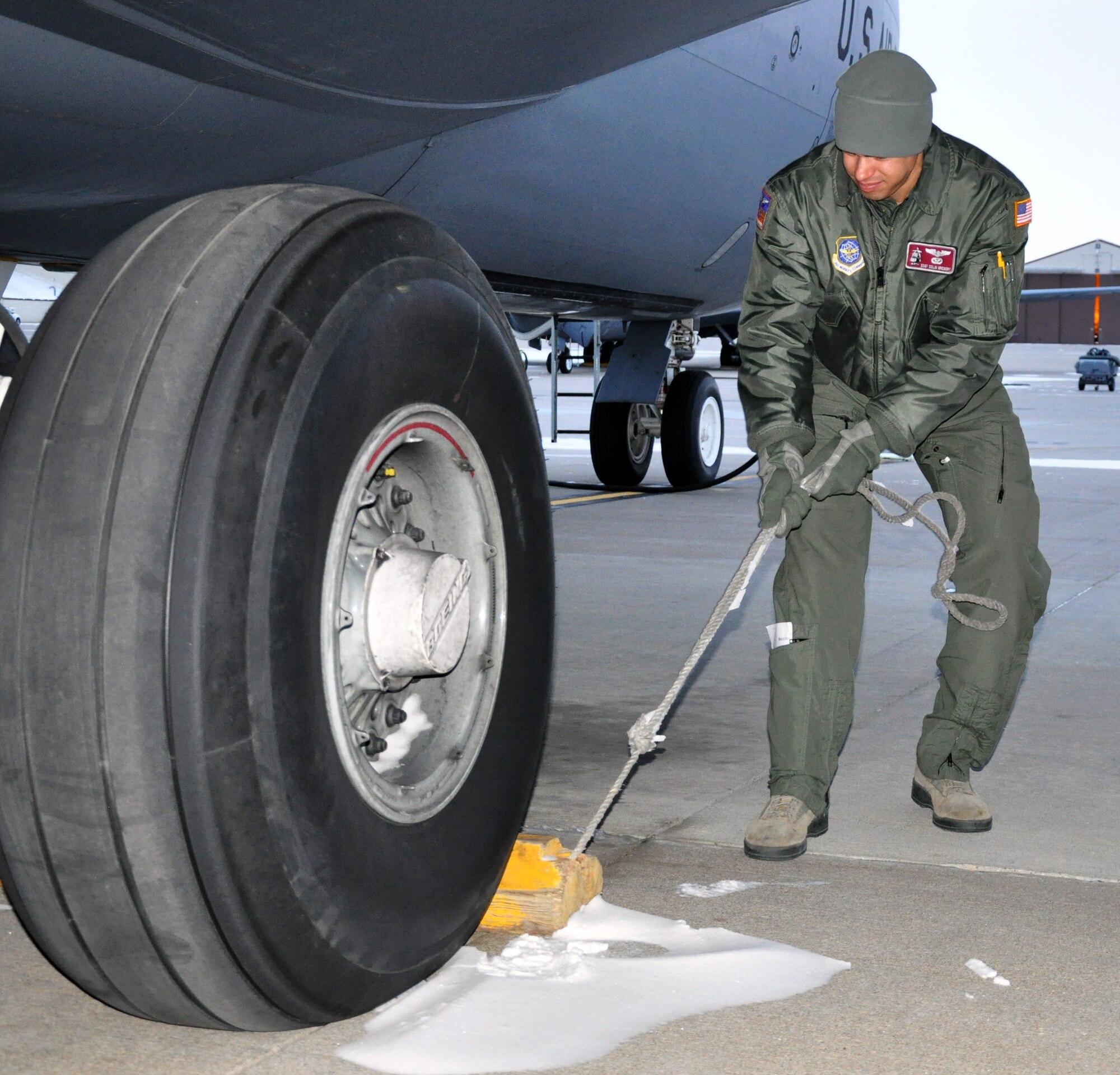 Staff Sgt. Colin Gregory, an air refueling boom operator assigned to the 344th Air Refueling Squadron, works to loosen a chock that was frozen into place against the tire of a KC-135 Stratotanker on the flightline at McConnell Air Force Base, Kan., Feb. 23, 2015.  Gregory was moving the chock as part of running a cargo loading checklist prior to loading the aircraft.  A total force team of logistics personnel and air refueling boom operators from the active duty 22 ARW and Air Force Reserve 931st Air Refueling Group braved sub-freezing temperatures to load approximately 18,000 pounds of cargo onto the aircraft in preparation for Red Flag. Red Flag is a large-scale military training exercise conducted at Nellis Air Force Base, Nev. (U.S. Air Force photo by Capt. Zach Anderson)  