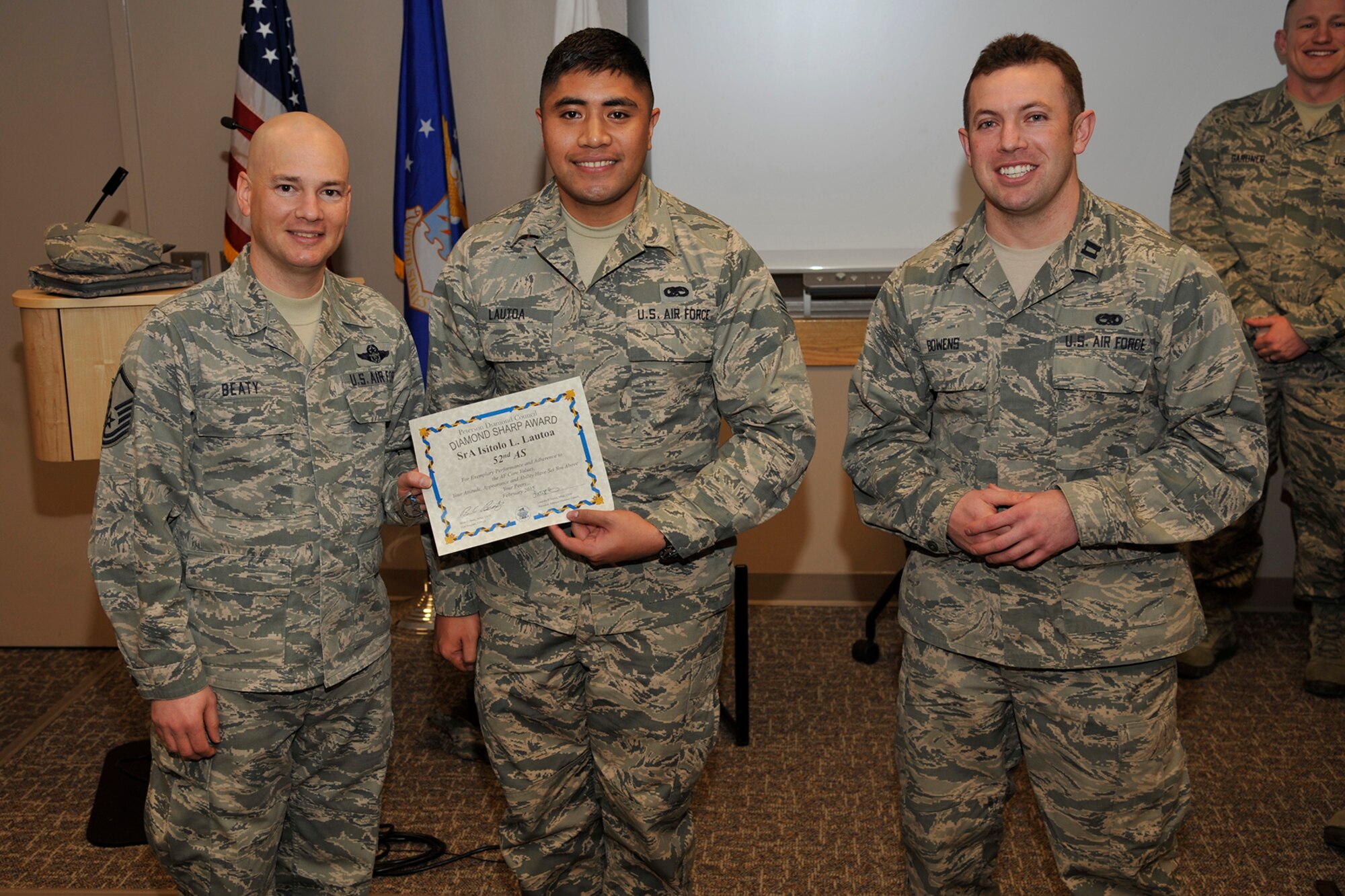 PETERSON AIR FORCE BASE, Colo. – Master Sgt. Brian Beaty (left) 52nd Airlift Squadron acting first sergeant, and Capt. Aaron Bowens (right), 52nd AS maintenance officer, present the Diamond Sharp award to Senior Airman Isitolo Lautoa, 52nd AS aircraft hydrualics systems specialist, Feb. 11. Lautoa led a “Redball” response team, identifying and replacing a steering control valve ahead of a two-hour standard, which enabled a presidential support mission. Additionally, he rebuilt and replaced a worn hydraulic test stand hose, saving the Air Force $300,000 for a new aircraft support equipment. (U.S. Air Force photo by Robb Lingley)