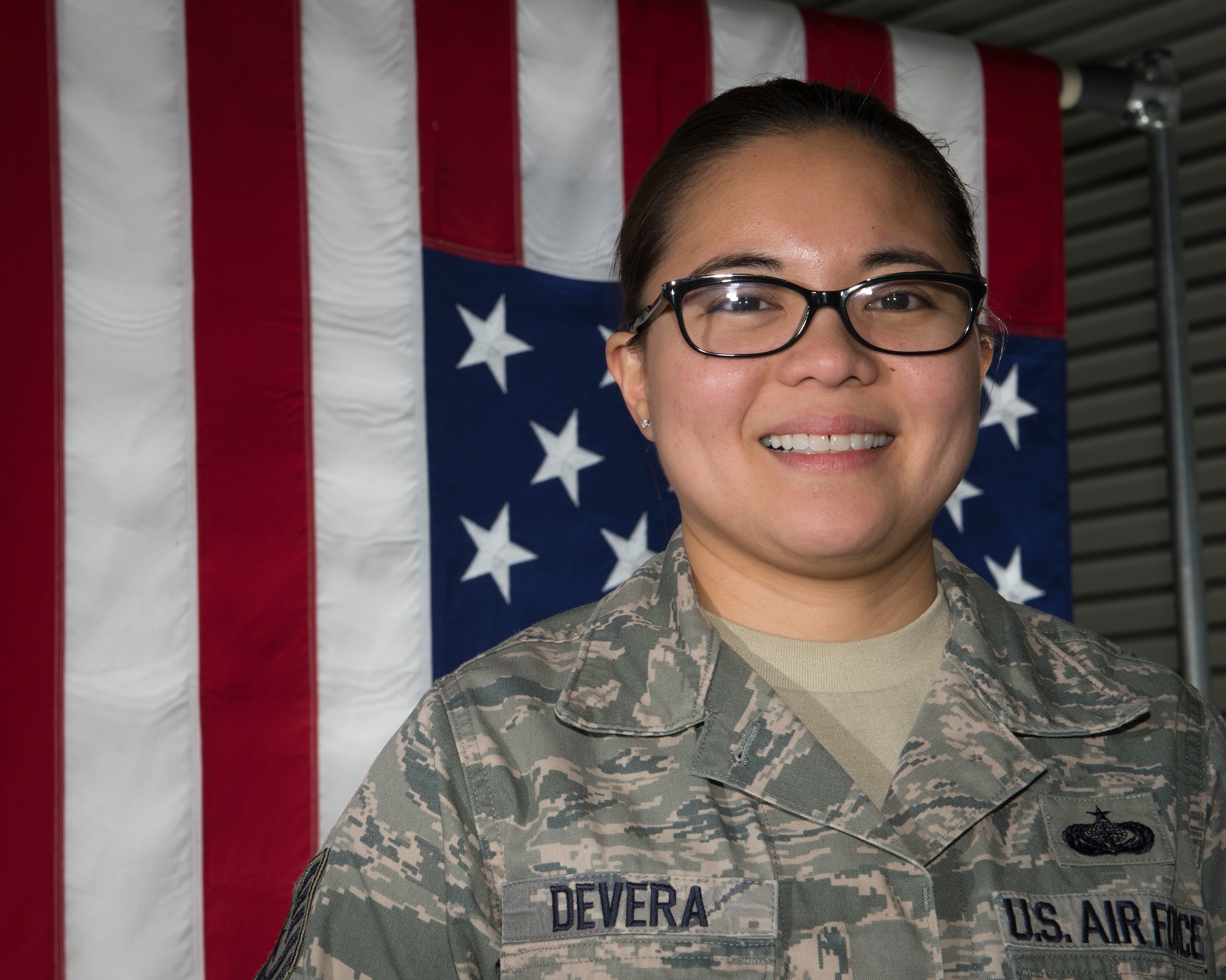 Tech. Sgt. Christine Devara poses in front of an American Flag in the departures section of the Charles C. Carson Center for Mortuary Affairs, Dover Air Force Base, Del., Feb. 23, 2015. Devara, currently serving on her seventh deployment to the mortuary, became a funeral director as a result of her experience here. She is a reservist with the 512th Memorial Affairs Squadron. (U.S. Air Force photo by Capt. Raymond Geoffroy)