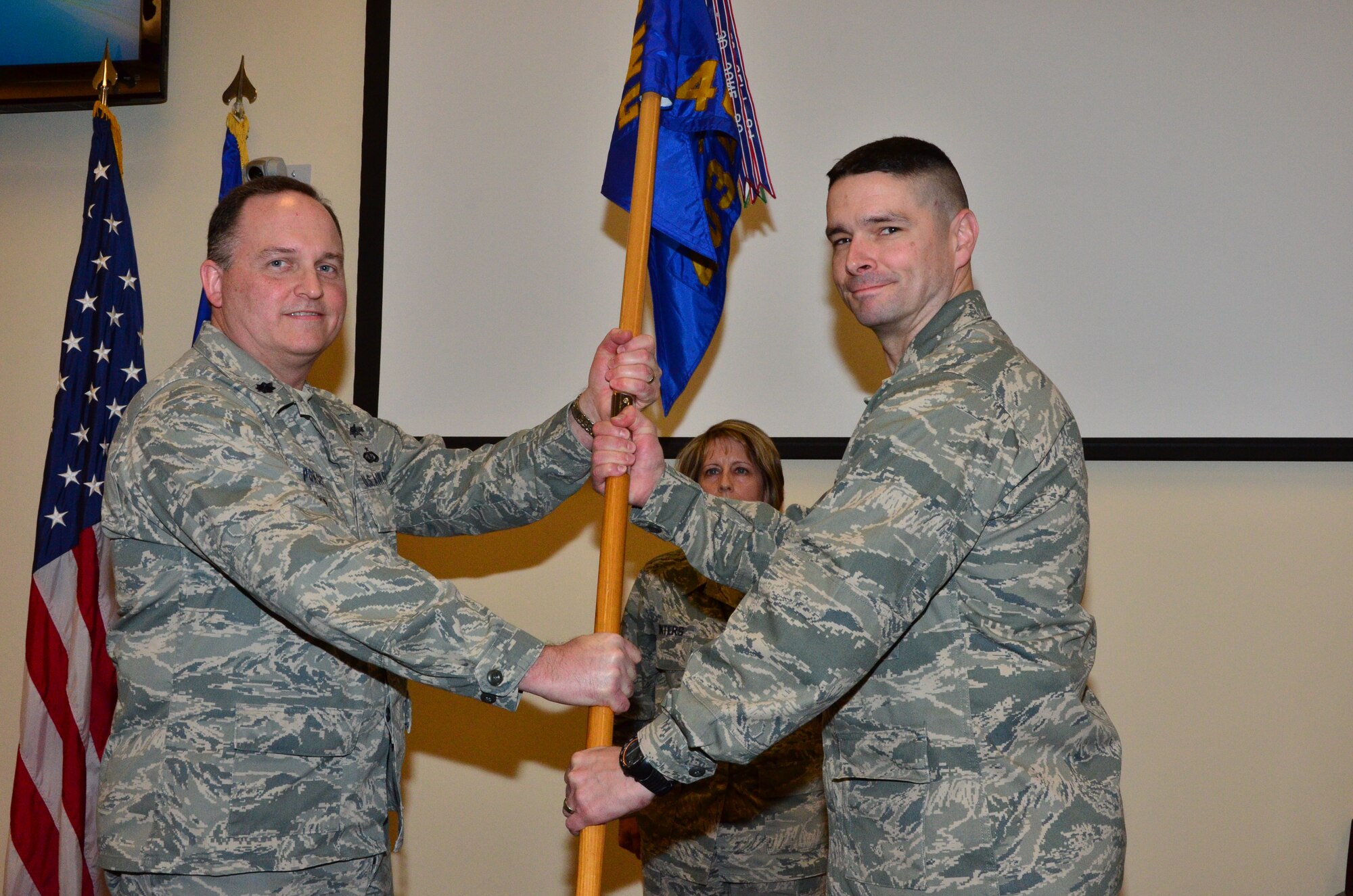 Lt. Col. Robert Poncet, 403rd Mission Support Group deputy commander, passes the 403rd Civil Engineering Squardon guidon to in coming 403rd CES Commander Maj. Quinton Sasnett during a change of command ceremony 7 Feb at the 815th Airlift Squadron auditorium.