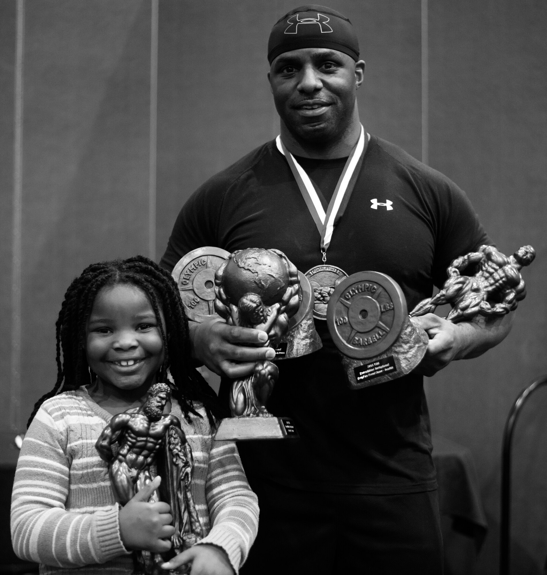 U.S. Navy Petty Officer 1st Class Jonathan Terrell Groves, event competitor, poses with his daughter at the 2015 Yokota Powerlifting Invitational held in the Samurai Fitness Center at Yokota Air Base, Japan, Feb. 21, 2015. Groves won six out of the possible six male awards at the competition's end. (U.S. Air Force photo by Airman 1st Class Delano Scott/Released)