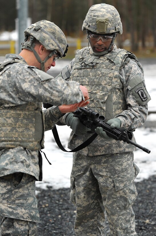 A U.S. Army range safety officer makes adjustments to a soldier's weapon during a weapons qualification training exercise at the 7th Army Joint Multinational Training Command's Grafenwoehr Training Area, Germany, Feb. 18, 2015.