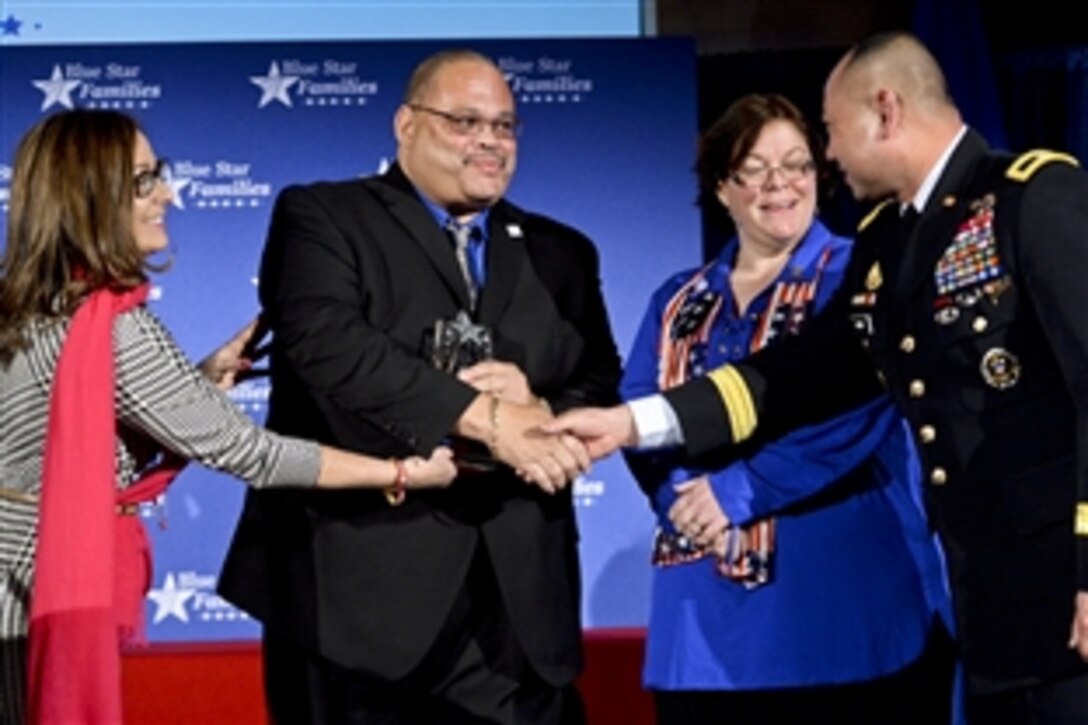 Army Brig. Gen. James Wong, right, congratulates Mark Johnson, second from left, the recipient of the Blue Star Neighbor Award, at the Blue Star Families Fifth Anniversary Celebration in Washington, D.C., Feb. 24, 2014. Wong is the assistant to the National Guard's acting director. Kathy Roth-Douquet, left, founder and CEO of Blue Star Families, and Kelly Durkee-Erwin, third from left, who nominated Johnson, participated in the event. 