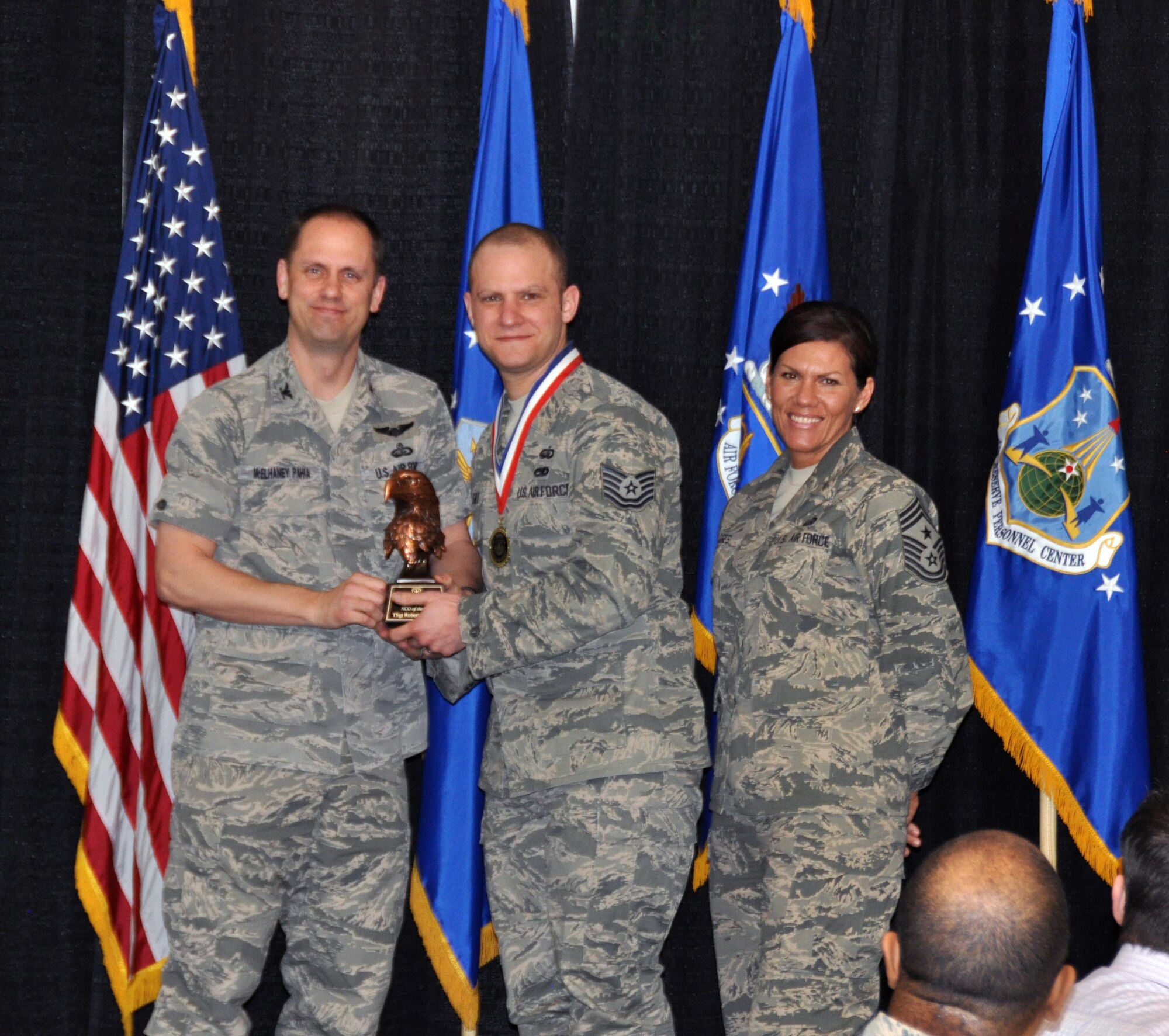 Col. Sean McElhaney Pahia, Air Reserve Personnel Center vice commander, and Chief Master Sgt. Ruthe Flores, ARPC command chief, present the ARPC Noncommissioned Officer of the Year award to Tech. Sgt. Robert Van Ghle. McElhaney Pahia honored ARPC’s 2014 outstanding performers of the year as well as their A1 annual award winners at the Summit Conference and Event Center Feb. 24, 2015, in Denver. (U.S. Air Force photo/Tech. Sgt. Rob Hazelett)