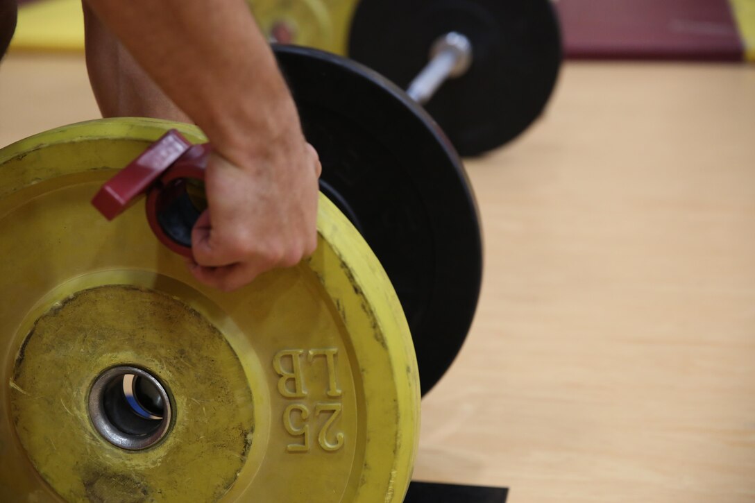 A Marine adjusts his weights between workouts during a High Intensity Tactical Training  instructor certification course at Hopkins Hall Gym at Camp Allen in Norfolk, Virginia, Feb. 10. Each exercise requires different weights to attain maximum achievement. The course teaches Marines how to properly and effectively instruct exercises associated with the three modules of HITT: Combat, Warrior and Athlete HITT. 