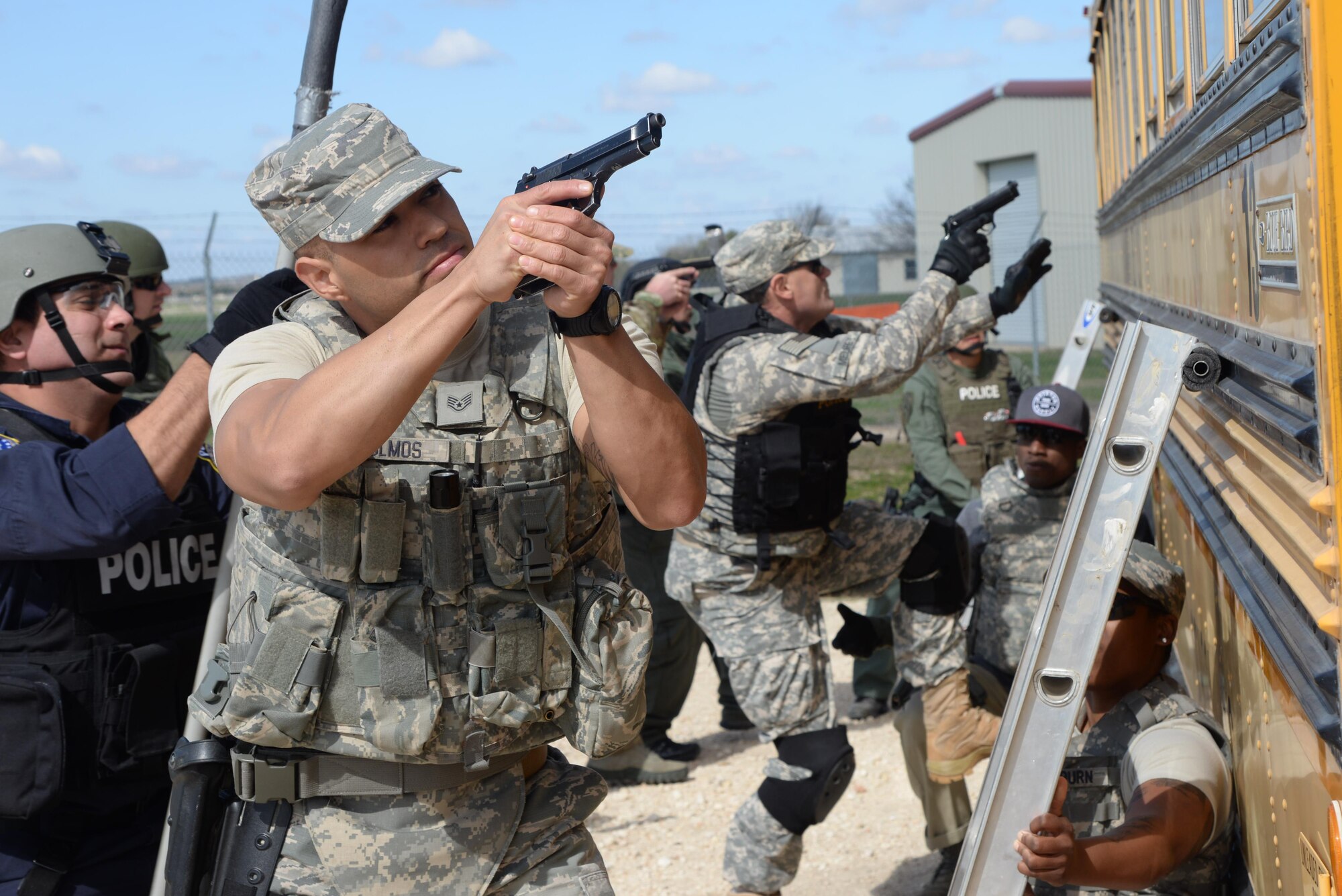 Staff Sgt. Paul Olmos III, 802nd Security Forces Squadron military working dog handler, leads members from the 902nd and 802nd SFS with members of local police departments during a bus assault and hostage rescue exercise Feb. 19, 2015 at Joint Base San Antonio-Randolph, Texas. The local agencies involved in the exercise were from the cities of Live, Oak Universal City and Converse and the Judson Independent School District Police Departments. Security Forces and local police departments trained together to prepare for emergencies that require both military and civilian response efforts. (U.S. Air Force photo by Airman 1st Class Stormy Archer)