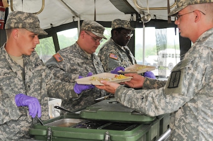 New York Army National Guard Spc. Steven Hoyt serves food to a fellow soldier during the Philip A. Connelly cooking competition evaluation on June 13, 2010. The days menu included roast turkey, gravy, Mexican corn, corn soup, salad, and Florida lemon cake with a cream cheese frosting.