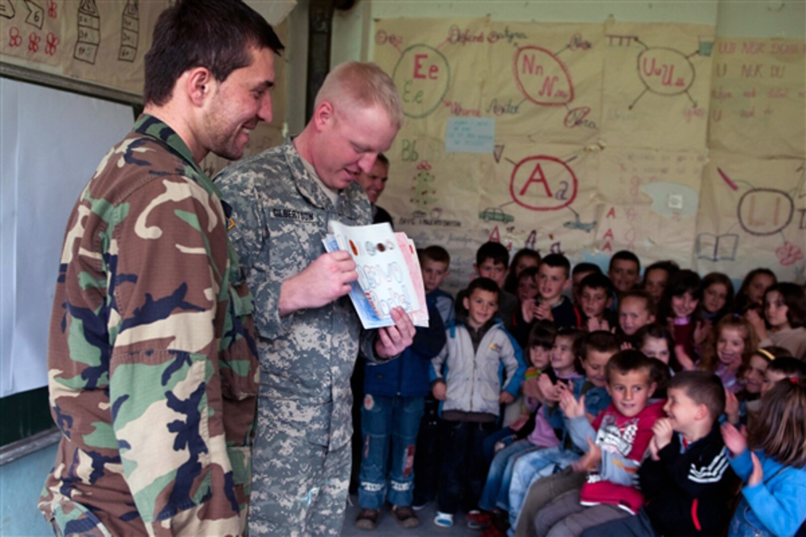 Army Staff Sgt. Andrew T. Gilbertson of the North Dakota National Guard displays artwork from students in Oakes, N.D., to students in Bicec, Kosovo, April 15, 2010.