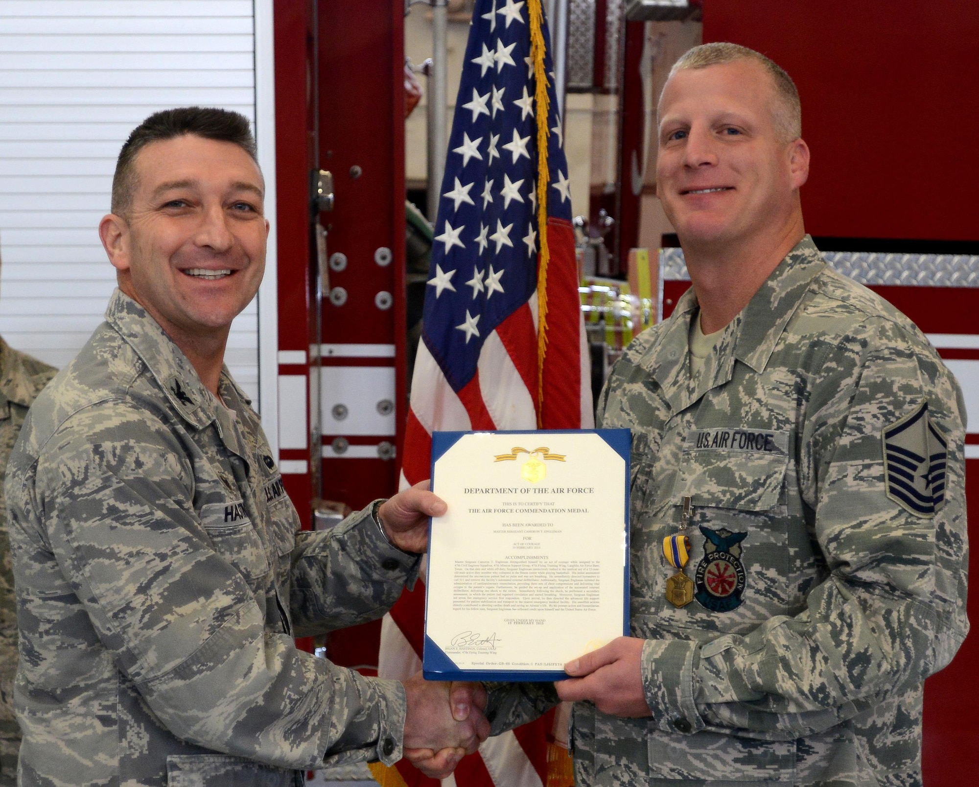 Master Sgt. Cameron Engleman is presented an Air Force Commendation Medal by Col. Brian Hastings, 47th Flying Training Wing commander at Laughlin Air Force Base, Texas, Feb. 25, 2015. Engleman's medal citation reads: Master Sergeant Cameron T. Engleman distinguished himself by an act of courage while assigned to the 47th Civil Engineer Squadron, 47th Mission Support Group, 47th Flying Training Wing, Laughlin Air Force Base, Texas.  On that date and while off-duty, Sergeant Engleman instinctively rushed to the medical aid of a 35-year-old male active duty member who collapsed in the fitness center while playing basketball.  His initial assessment determined the unconscious patient had no pulse and was not breathing.  He immediately directed bystanders to call 911 and retrieve the facility's automated external defibrillator. Additionally, Sergeant Engleman initiated the administration of cardiopulmonary resuscitation, providing three sets of chest compressions and delivering vital oxygen to the patient's organs. Furthermore, he guided the set-up and application of the automated external defibrillator, delivering one shock to the victim.  Immediately following the shock, he performed a secondary assessment, in which the patient had regained circulation and started breathing.  Moreover, Sergeant Engleman led seven fire emergency service first responders.  Upon arrival, he then directed the advanced life support personnel for patient stabilization and transport to the nearest emergency medical facility.  His unselfish actions directly contributed to aborting cardiac death and saving an Airman's life.  By his prompt action and humanitarian regard for his fellowman, Sergeant Engleman has reflected credit upon himself and the United States Air Force. (U.S. Air Force photo by Staff Sgt. Steven Doty)
