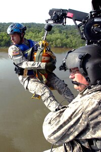 Sgt. David Tillman, right, a crew chief with the Oklahoma National Guard's Company C, 2nd Battalion, 149th Aviation Regiment, prepares to lower Sgt. Richard Pindel, a flight medic also with Company C, into Lake Thunderbird on a water penetrator hoist. The two Oklahoma Guardsmen participated in over-water training to perfect their skills in rescuing victims stranded in the water June 6.