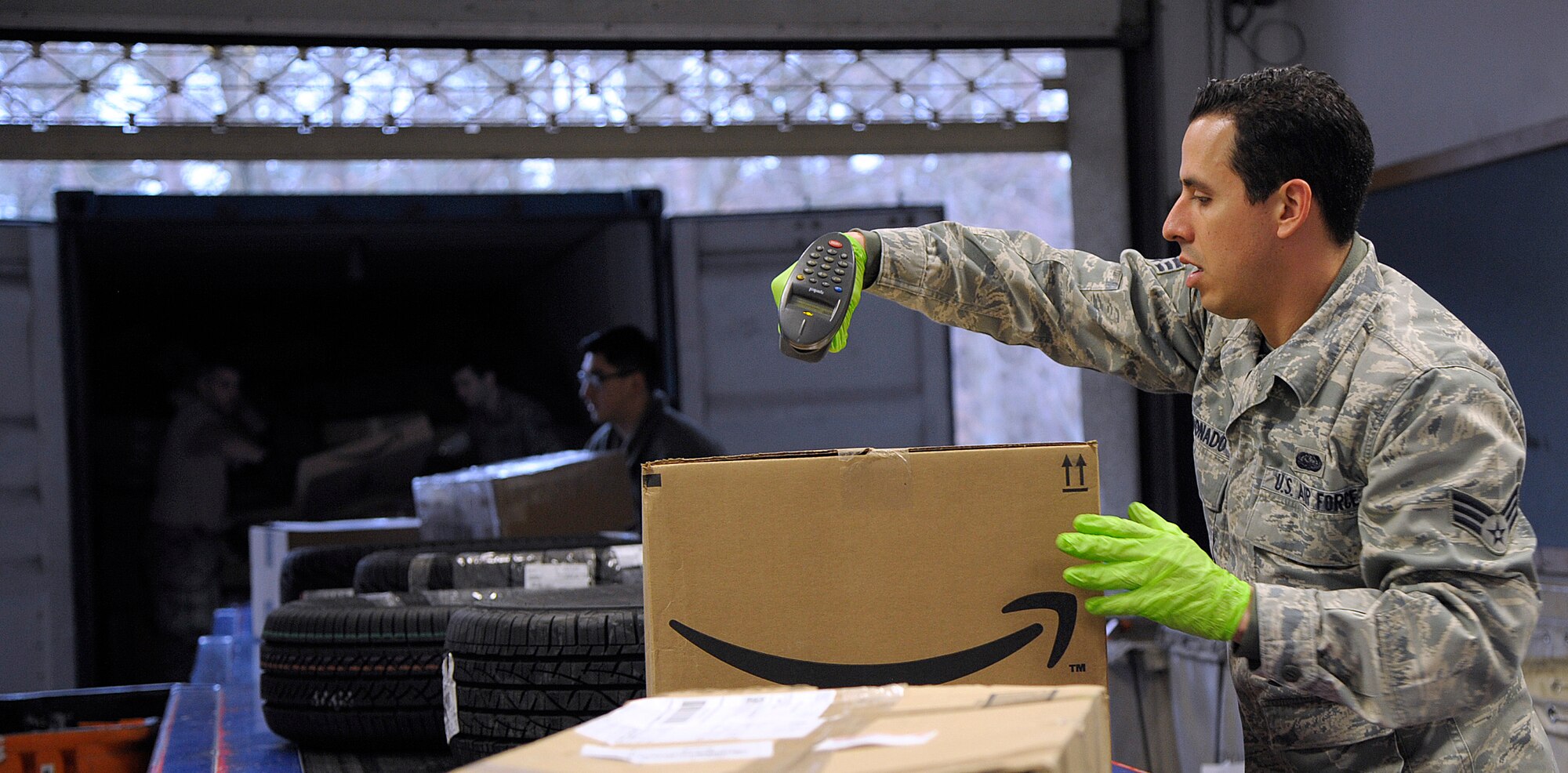 Senior Airman Joseph Maldonado, 86th Communications Squadron postal specialist, scans a package as other postal specialists unload mail Feb. 19, 2015. The Northside Post Office is the largest Department of Defense postal operation, handling approximately eight million pounds of mail annually. (U.S. Air Force photo/Senior Airman Timothy Moore)