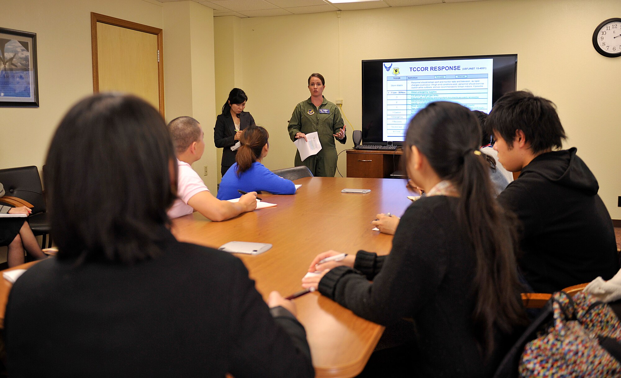 U. S. Air Force Capt. Elizabeth Hudson, 909th Air Refueling Squadron chief of wing plans and KC-135 Stratotanker pilot, briefs students from the Okinawa International University about the U. S. military's typhoon response procedures during a base visit to Kadena Air Base, Japan, Feb. 23, 2015. The students currently study disaster prevention measures at the Okinawa International University and have interests in learning about the U.S. military's response to disasters. (U.S. Air Force photo by Naoto Anazawa)